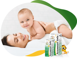 Two packs of Espumisan 100 mg Emulsion in different sizes in the foreground, behind the big package is an illustrated lion. In the background there is a happy baby that lies on his smiling mother and looking curiously at the camera