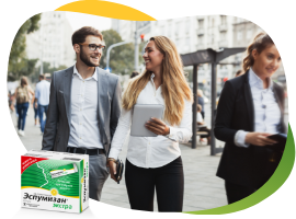 Two young women and a young man in business outfit walking through the city vigorously, in the foreground is a pack of Espumisan Easy
